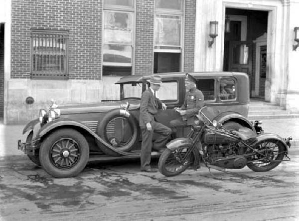 Traffic officer with Auto Stutz Police Cycle in front of headquarters building 1928.